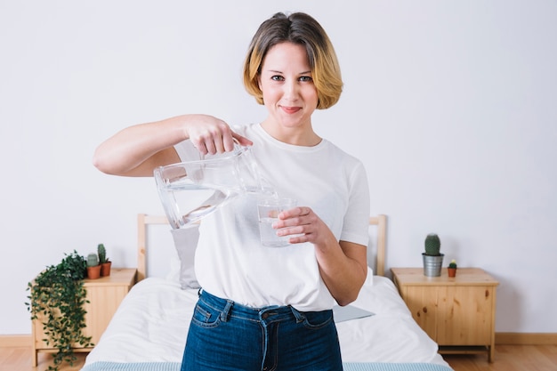 Photo gratuite femme verser de l'eau et regarder la caméra