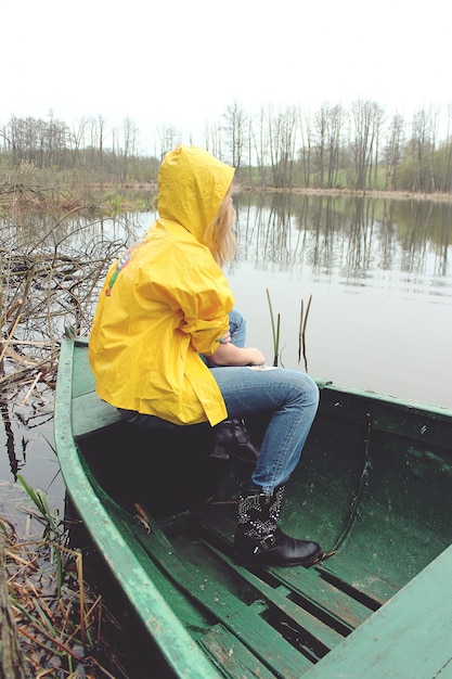 Photo gratuite femme avec veste jaune assis dans un bateau