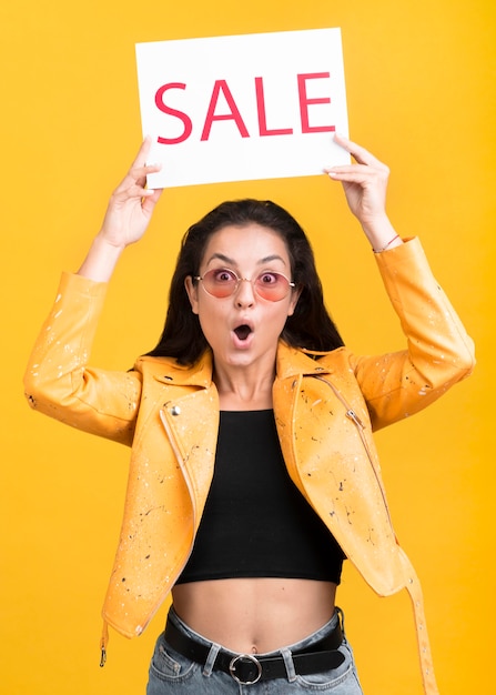 Femme en veste jaune tenant une bannière de vente