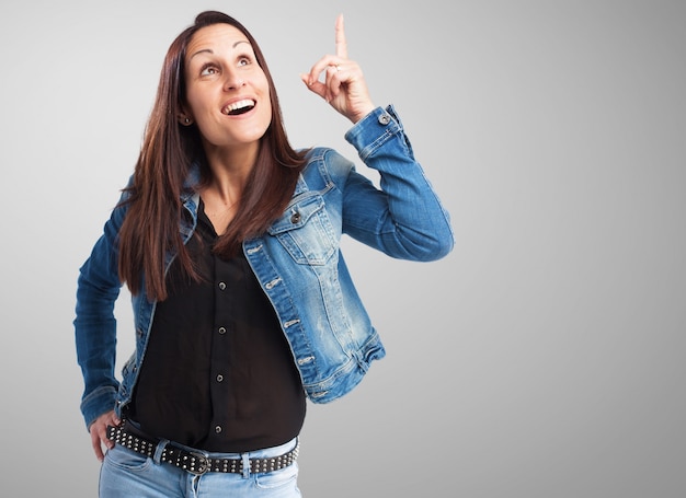 Femme en veste en jean pointant vers le haut