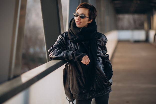 Femme en veste noire marchant à travers le pont