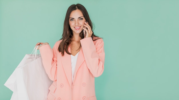 Femme en veste rose avec des sacs à provisions et smartphone