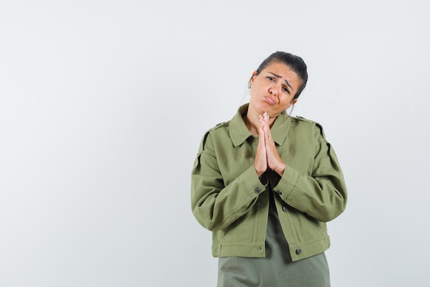 Photo gratuite femme en veste, t-shirt montrant le geste de namaste et l'air innocent