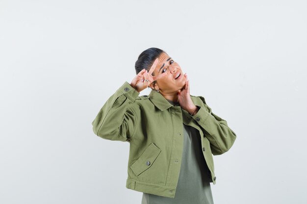 Femme en veste, t-shirt montrant le geste de la victoire et à la confiance