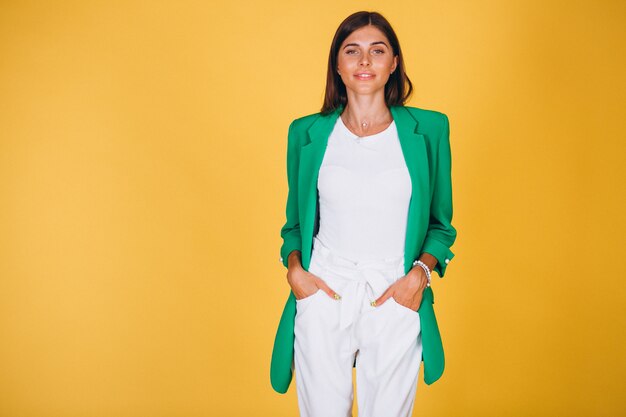 Femme en veste verte en studio sur fond jaune