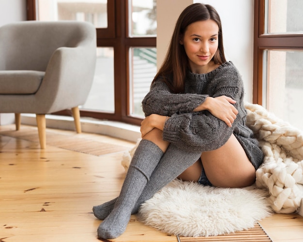 Femme en vêtements confortables assis sur un tapis