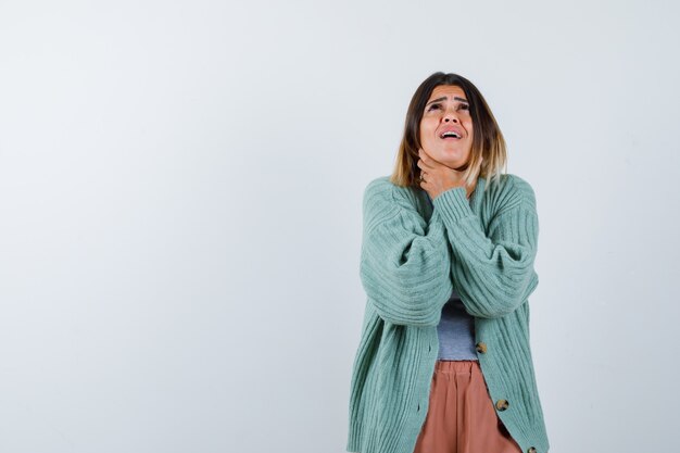 Femme en vêtements décontractés souffrant de maux de gorge et à la vue douloureuse, de face.