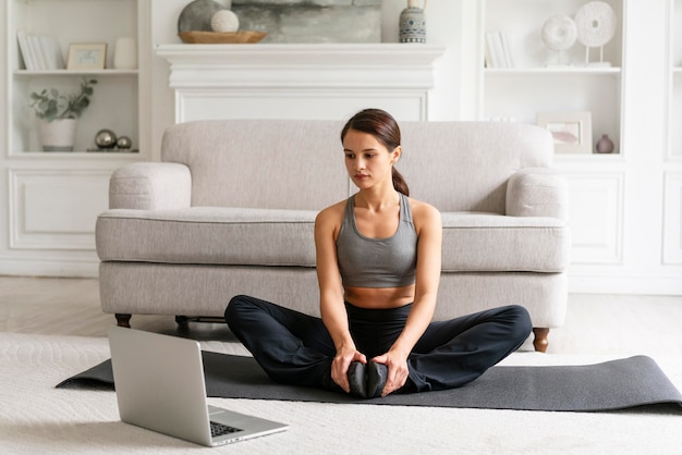 Femme en vêtements de sport faisant de l'exercice à la maison