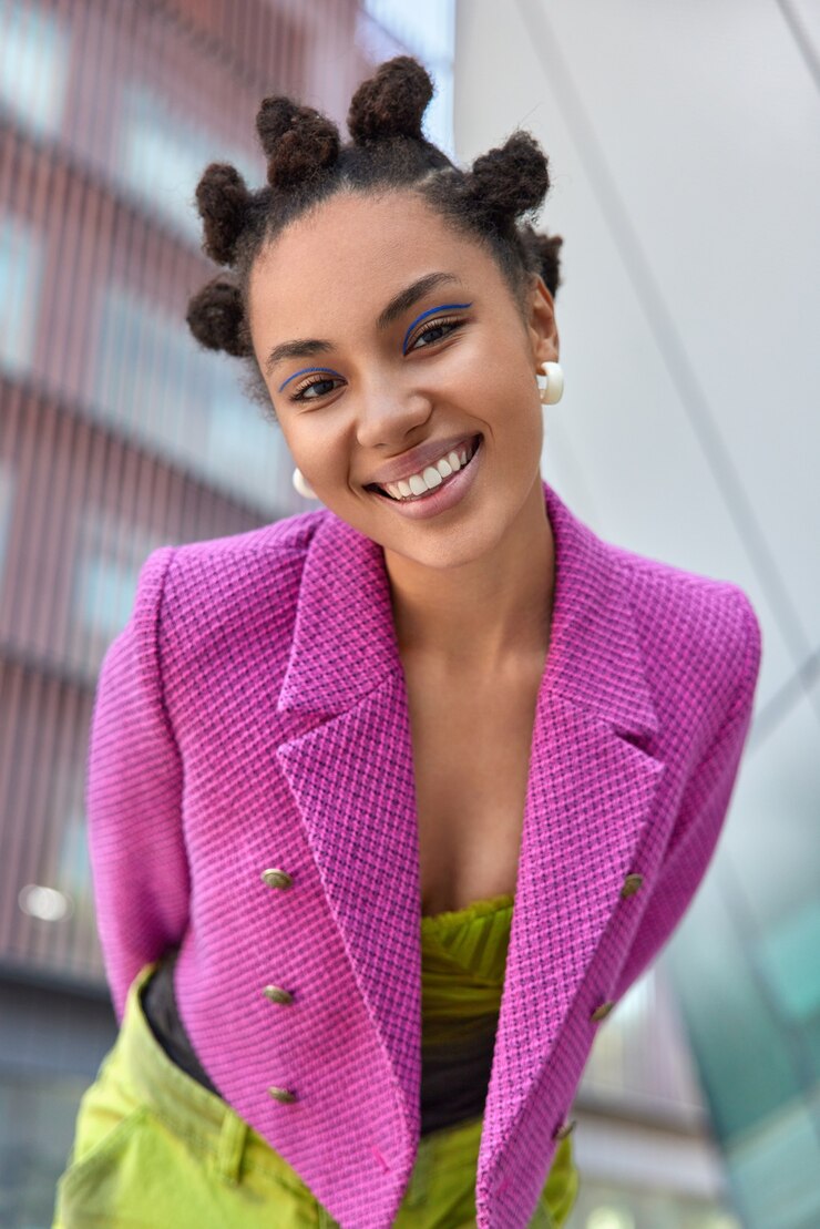 Photo gratuit une femme vêtue d'une veste rose exprime des émotions positives se sent bien marcher dans un lieu urbain pose à l'extérieur sur fond flou