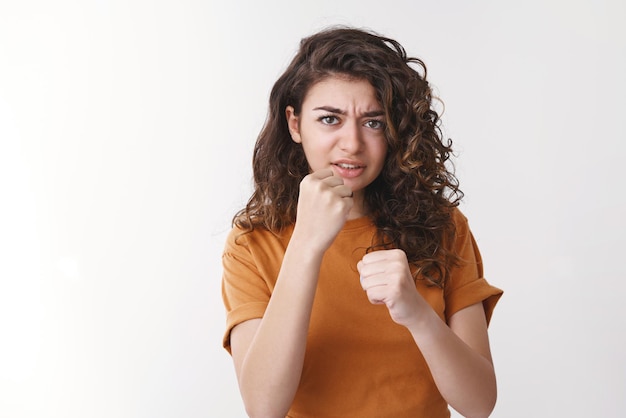 Femme veux frapper vous lever les poings debout boxe défensive pose regarder en colère contre caméra se défendre se défendre insulté