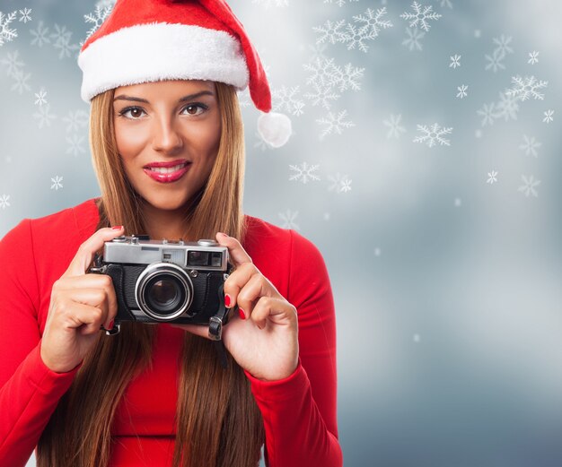 Femme avec un vieil appareil photo dans un fond de flocons de neige