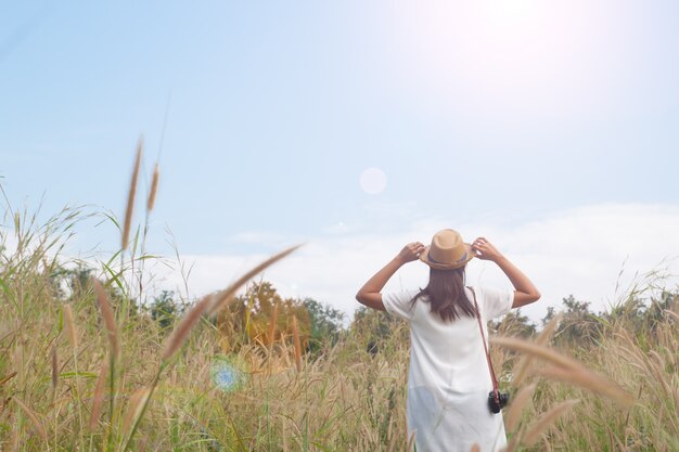 Femme voyageur avec un chapeau de prise de caméra et respiration sur le champ des graminées et de la forêt, concept de voyage Wanderlust, espace pour le texte, moment épique atmosphérique