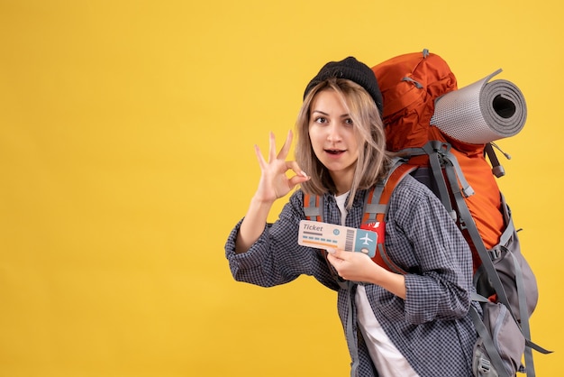 femme voyageur avec sac à dos tenant un billet faisant signe okey