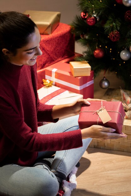 Femme vue de côté en admirant les cadeaux qu'elle a emballés