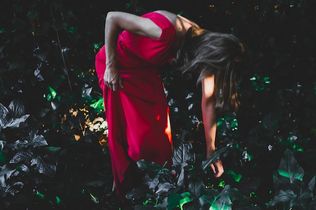 Femme de vue de côté touchant l&#39;herbe dans le jardin