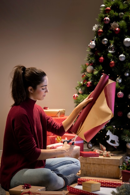 Photo gratuite femme vue de face à la maison, emballant des cadeaux