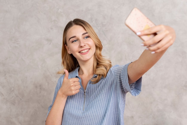 Femme vue de face prenant un selfie avec son téléphone