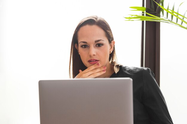 Femme vue de face à la recherche de son ordinateur portable stressé