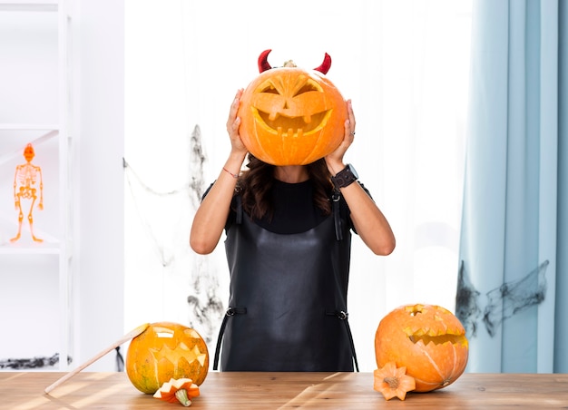 Femme vue de face tenant une citrouille sculptée pour halloween