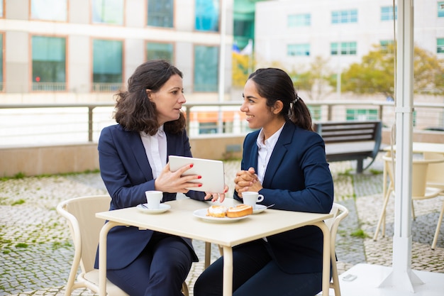 Femmes d'affaires, boire du café et utiliser un tablet pc