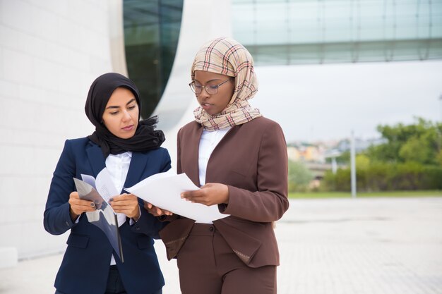 Femmes d'affaires ciblées marchant dans la rue et inspectant les documents