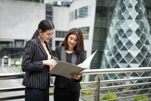 Les femmes d&#39;affaires discutent de la paperasserie contre la balustrade. Concept des entreprises.