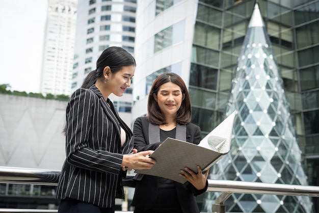 Photo gratuite les femmes d'affaires discutent de la paperasserie contre la balustrade. concept des entreprises.