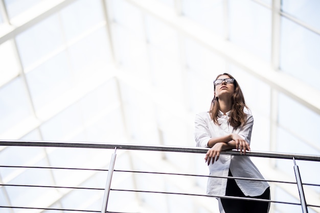 Femmes D'affaires Prospères Debout Regardant à Travers Le Balcon Dans Un Centre De Bureau Moderne Habillé En T-shirt Blanc