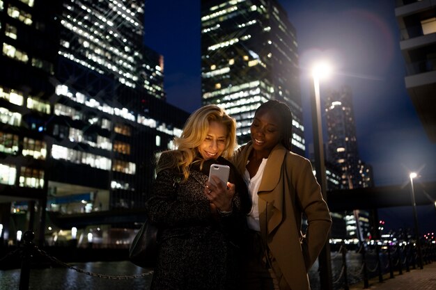 Femmes d'affaires se réunissant dehors la nuit dans la ville