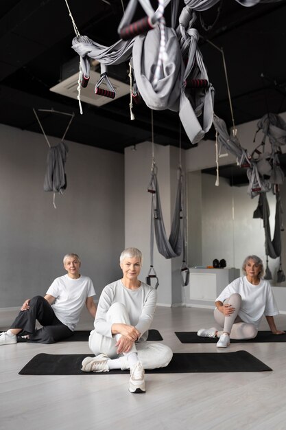 Femmes âgées faisant des exercices de fitness à la salle de sport sur des tapis de yoga