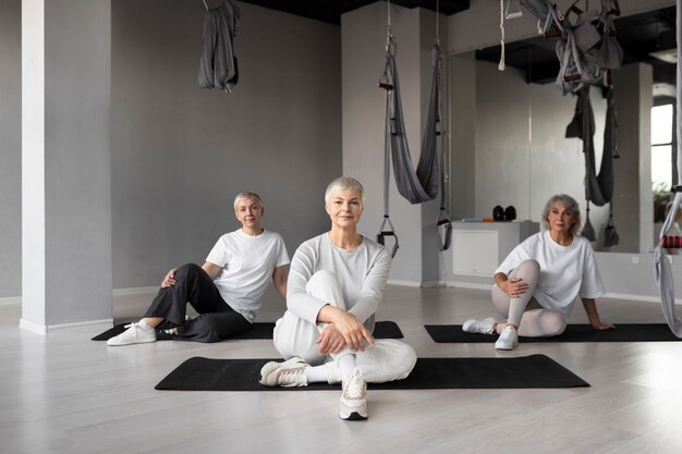 Femmes âgées faisant des exercices de fitness à la salle de sport sur des tapis de yoga