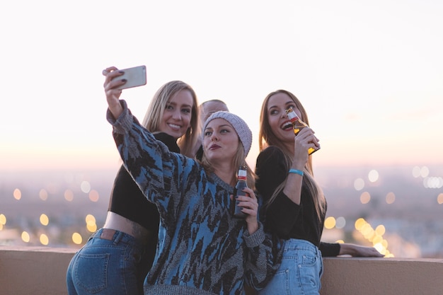 Femmes avec de la bière prenant selfie sur le toit