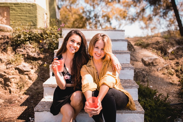 Femmes avec des boissons assis sur les marches