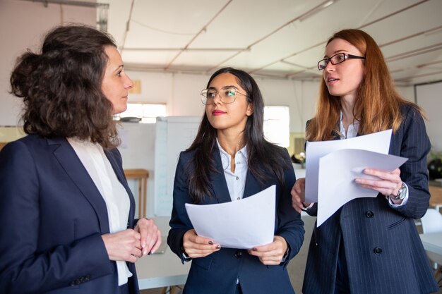 Photo gratuite femmes ciblées avec des documents posant des questions à un collègue mature