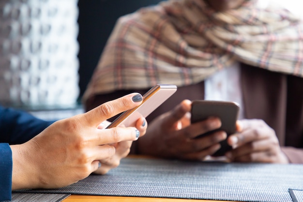 Femmes collègues discutant sur les téléphones dans un café