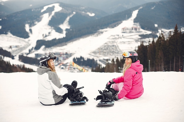 Photo gratuite femmes en costume de snowboard. sportives sur une montagne avec un snowboard dans les mains à l'horizon. concept sur le sport