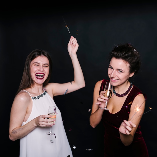 Photo gratuite femmes avec des coupes de champagne et des feux de bengale