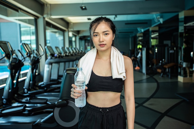 Les femmes debout et se détendre après l'exercice, en tenant une bouteille d'eau.