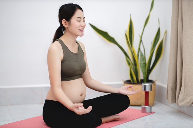 Portrait De Jolie Femme Enceinte Assise Faisant Des Exercices De Yoga En Position Du Lotus Dans La Salle De Sejour Photo Premium