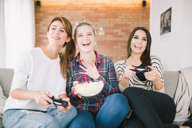 Des femmes excitées se prélasser avec un jeu vidéo et une collation
