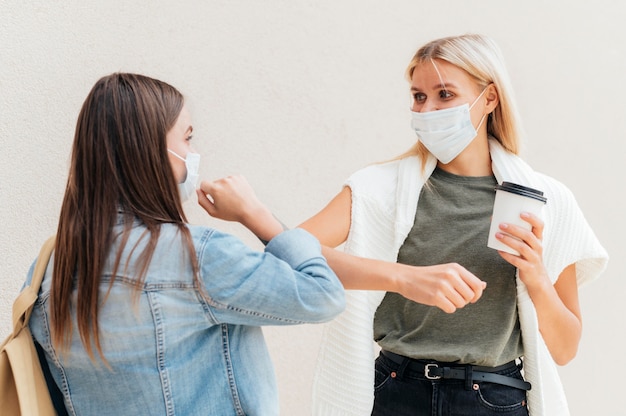 Femmes faisant un coup de coude avec distance sociale