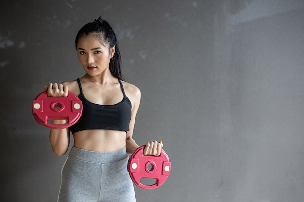 Photo gratuite femmes faisant de l'exercice avec deux disques d'haltères