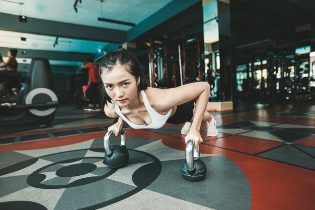 Les femmes faisant de l'exercice en poussant le sol avec la Kettlebell dans la salle de sport.