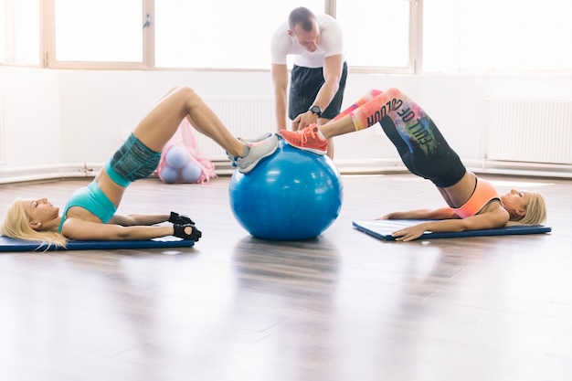 Photo gratuite femmes faisant des exercices en utilisant fitball avec entraîneur