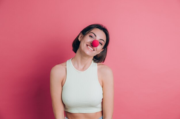 Femmes sur fond rose assez drôle et souriante jeune femme portant le nez de clown, ambiance de fête