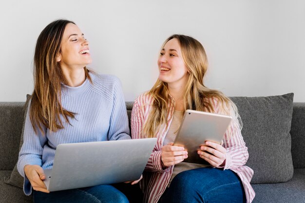 Femmes gaies avec tablette et ordinateur portable