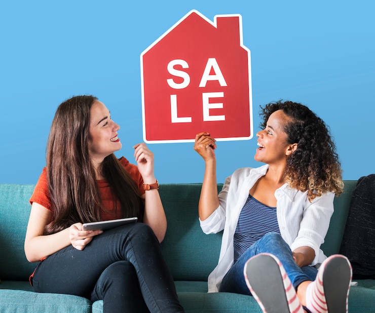 Photo gratuit femmes gaies tenant une icône de vente de maison
