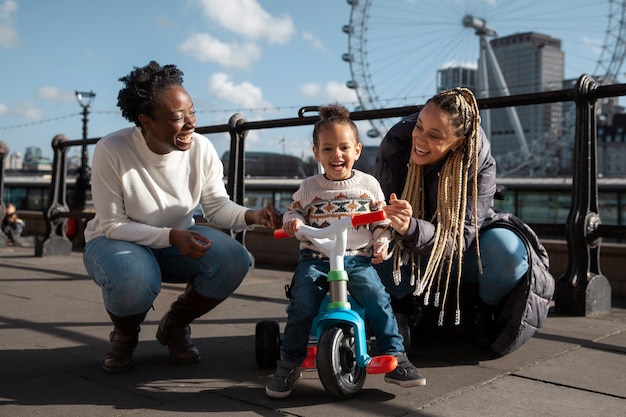 Photo gratuite femmes heureuses et enfant avec tricycle plein coup