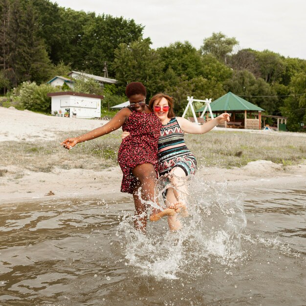 Femmes heureuses jouant avec de l'eau à la plage