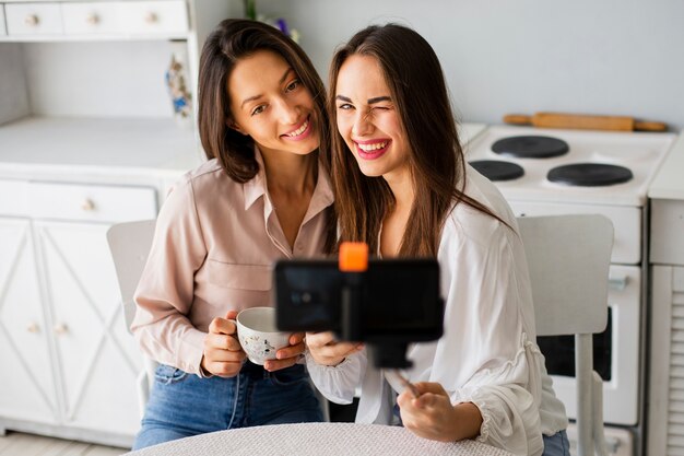 Femmes heureuses à la maison prenant des selfies